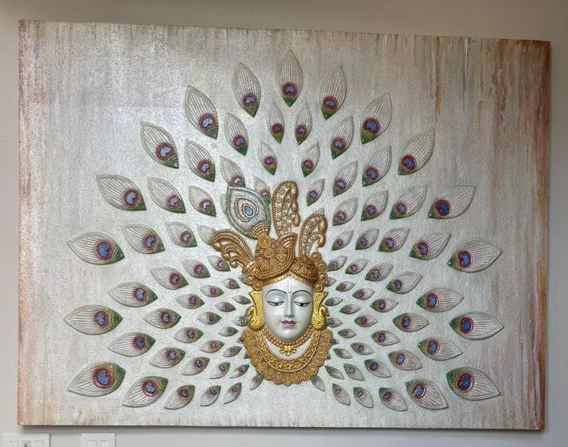 Relief artwork with peacock feathers around a gilded face